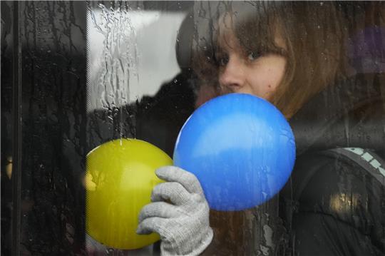 Ein Kind sitzt am Fenster eines Busses am polnisch-ukrainischen Grenzübergang Medyka und hält Luftballons in den Farben der ukrainischen Nationalflagge in den Händen. Symbolbild: Sergei Grits/AP/dpa