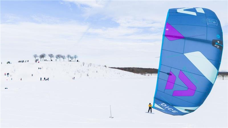 Ein Kite-Surfer gleitet am Kronsberg mit seinem Board über den Schnee.