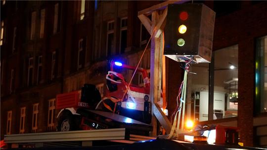 Ein Kleinlaster hat einen Holzgalgen aufs Dach geschnallt, an dem eine Ampel befestigt ist.