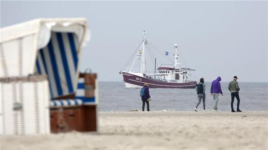 Ein Krabbenkutter fährt auf der Nordsee am Strand von St. Peter-Ording entlang.