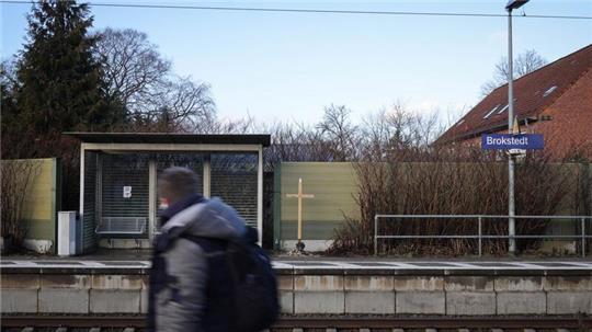 Ein Kreuz mit den Namen der Opfer der Messerattacke ist neben dem Wartehäuschen des Bahnhofs in Brokstedt aufgestellt.