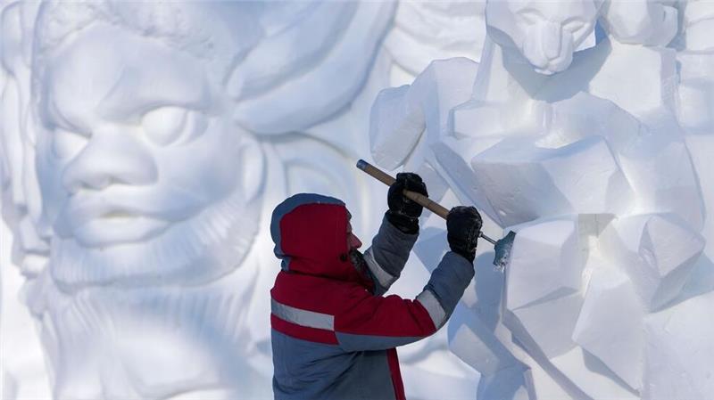 Ein Künstler arbeitet im chinesischen Harbin während eines Festivals, auf dem Schneeskulpturen gezeigt werden, an einem Kunstwerk aus Schnee und Eis.