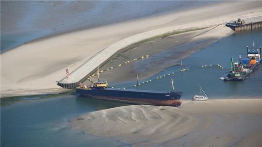 Ein Küstenmotorschiff liegt quer in der Hafeneinfahrt Wangerooge.