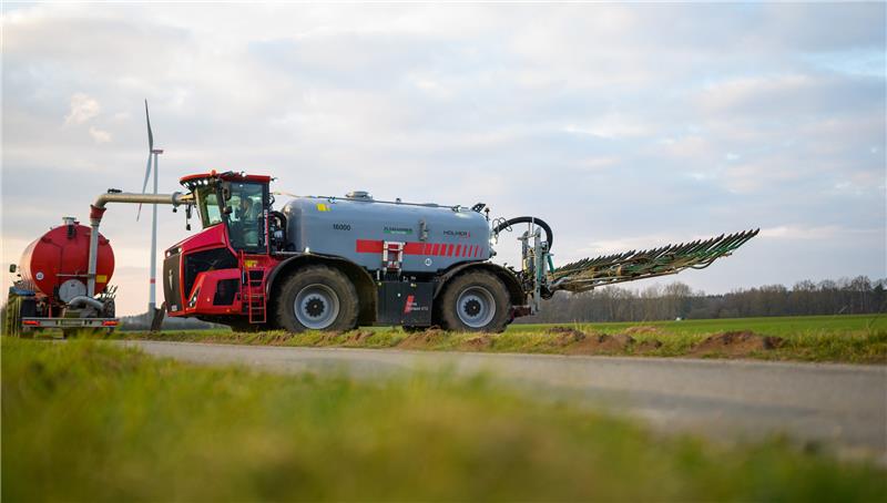 Ein Landwirt betankt sein Gespann (r) zum Gülle ausfahren an einem sogenannten Zubringerfahrzeug (l). Foto: Philipp Schulze/dpa