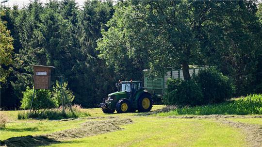 Ein Landwirt fährt mit Traktor über eine Wiese nahe des Fundortes einer Kinderleiche.