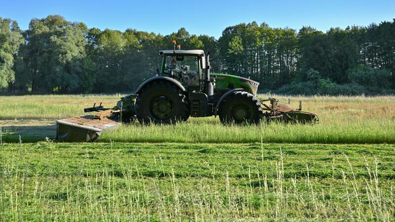 Ein Landwirt mäht am frühen Morgen eine Wiese.