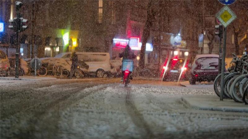Ein Lieferdienstfahrer fährt auf einer verschneiten Straße in der Innenstadt von Köln.