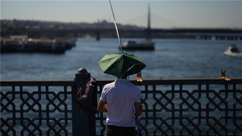 Ein Mann angelt an einem heißen Sommertag auf der Galata-Brücke in Istanbul.