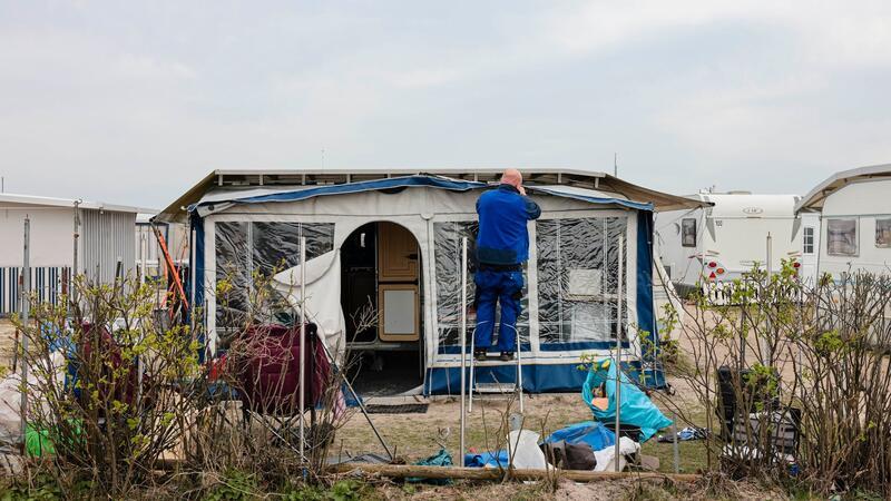 Ein Mann arbeitet an einem Vorzelt auf dem Campingplatz Ostseecamping in Schubystrand.