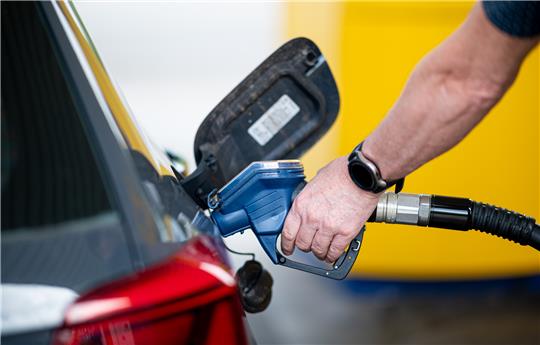 Ein Mann betankt an einer Tankstelle sein Auto. Wer auf dem Weg in die Sommerferien an der Autobahnraststätte tankt, zahlt häufig deutlich drauf. Foto: Daniel Reinhardt/dpa