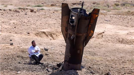 Ein Mann betrachtet das Wrack einer Rakete, die nach einem iranischen Angriff im Westjordanland aus dem Boden ragt.