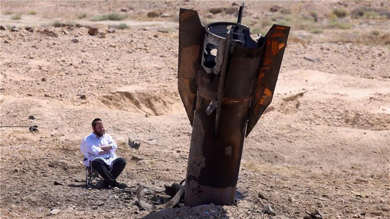 Ein Mann betrachtet das Wrack einer Rakete, die nach einem iranischen Angriff im Westjordanland aus dem Boden ragt.