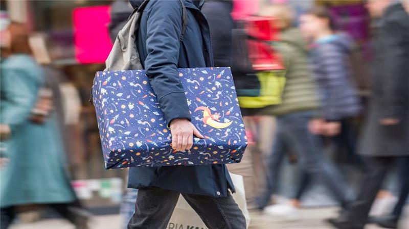 Ein Mann eilt mit einem verpackten Geschenk zwischen den anderen Passanten die Einkaufsmeile Zeil entlang. (zu dpa: «Im Schnitt 3.000 Euro Weihnachtsgeld für Tarifbeschäftigte»)