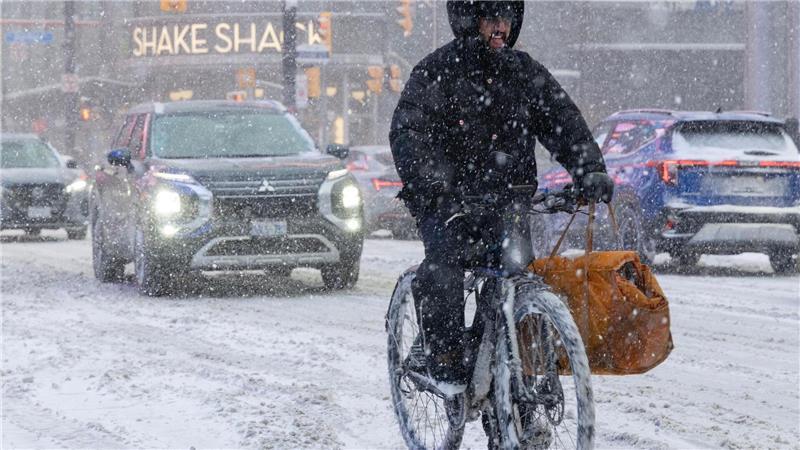Ein Mann fährt an einem verschneiten Tag in Toronto auf einem E-Bike.