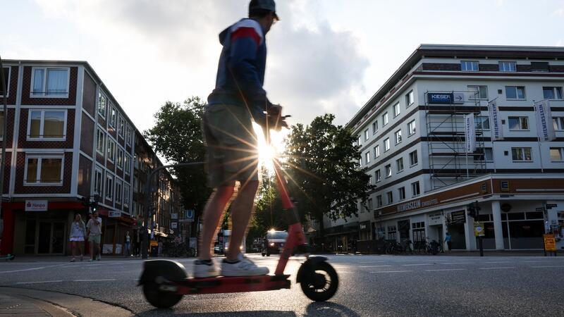 Ein Mann fährt auf einem E-Tretroller.