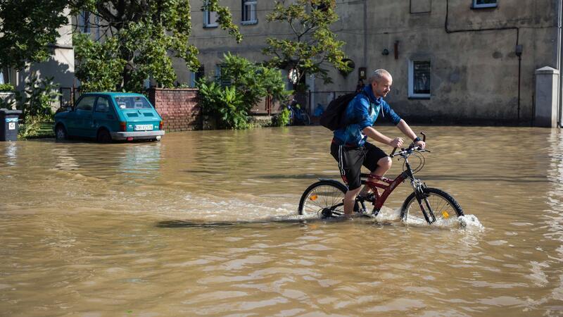 Zahl der Toten bei Hochwasser steigt auf mindestens 23 Ein Mann fährt mit dem Fahrrad durch eine überflutete Straße in der Stadt Lewin Brzeski im Süden Polens. (Foto aktuell)