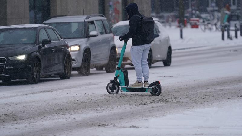 Feuerwehreinsatz beendet: S-Bahn-Verkehr auf Linie S3 weiter gestört Ein Mann fährt mit einem E-Scooter über eine verschneite Straße.