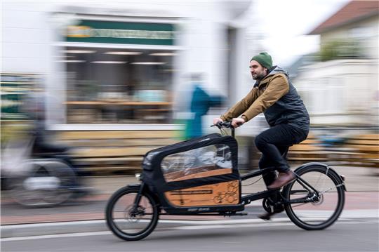 Ein Mann fährt mit einem Lastenrad durch die Stadt (Symbolbild). Foto: Sina Schuldt/dpa