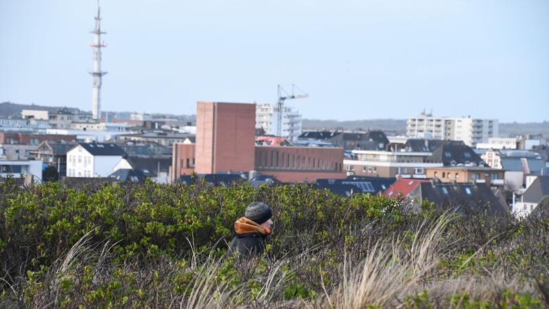 Ein Quadratmeter auf Sylt kostet im Schnitt über 14.400 Euro Ein Mann geht auf einem Weg über die Dünen.