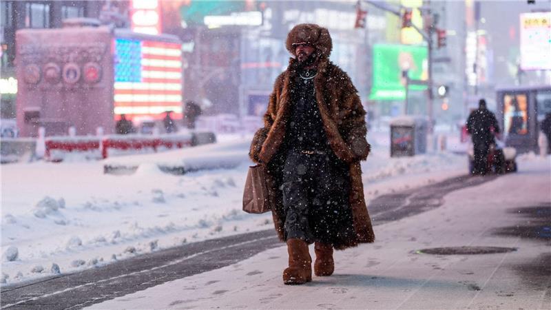 Ein Mann geht während eines Schneesturms über den Times Square in New York.