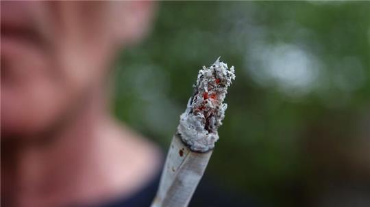 Ein Mann hält einen Joint.