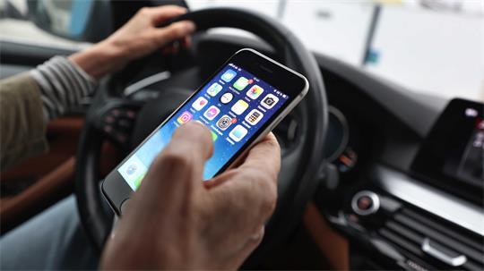 Ein Mann hält während der Autofahrt ein Smartphone in der rechten Hand. Vor dem Amtsgericht Buxtehude musste sich deshalb ein Autofahrer verantworten.