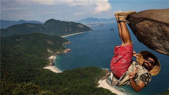 Ein Mann hängt für ein Bild an dem Felsen „Pedra do Telegrafo“ bei Rio de Janeiro.