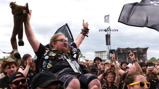Ein Mann in einem Rollstuhl wird beim Crowdsurfen durch die Menge getragen.