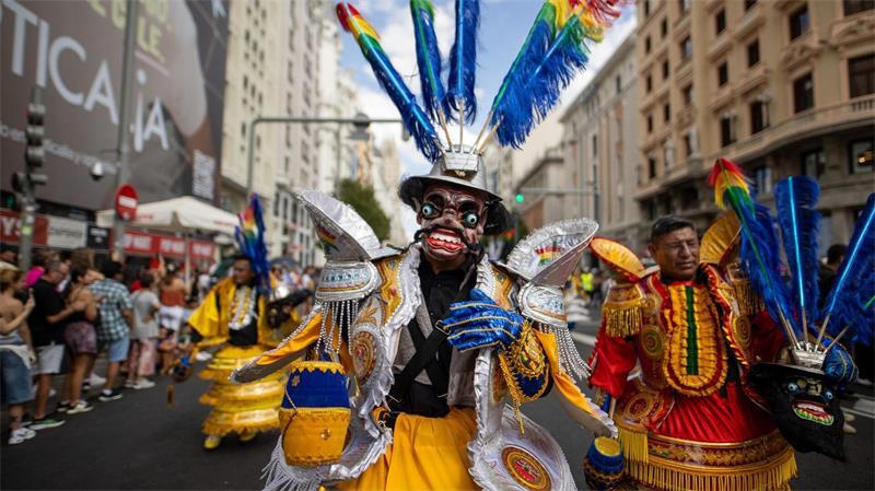 Ein Mann in traditioneller bolivianischer Tracht zieht in Madrid durch die Straßen.