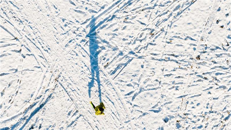 Ein Mann joggt am Kronsberg und wirft einen langen Schatten (Luftaufnahme mit Drohne).