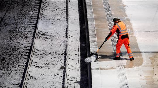 Ein Mann räumt am Hauptbahnhof in Hamburg auf einem Bahnsteig Schnee.