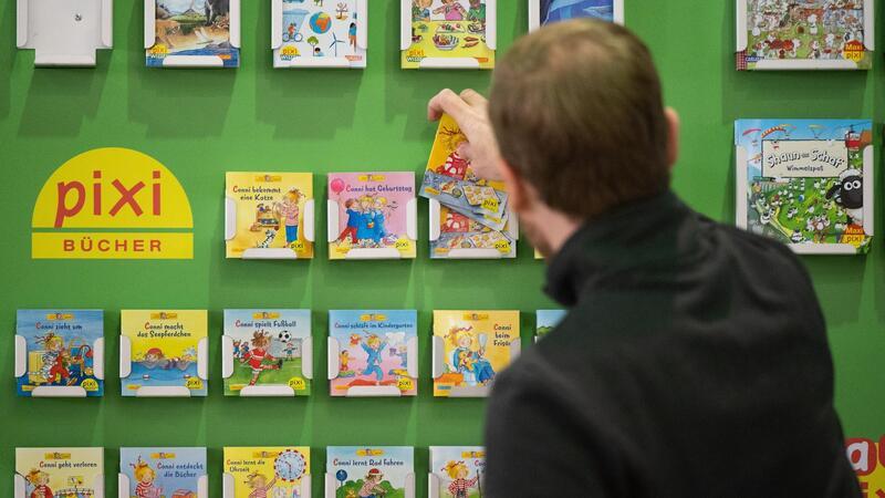 70 Jahre „Pixi“: Jubiläumsausstellung in Hamburg Ein Mann räumt pixi Kinderbücher in ein Regal.
