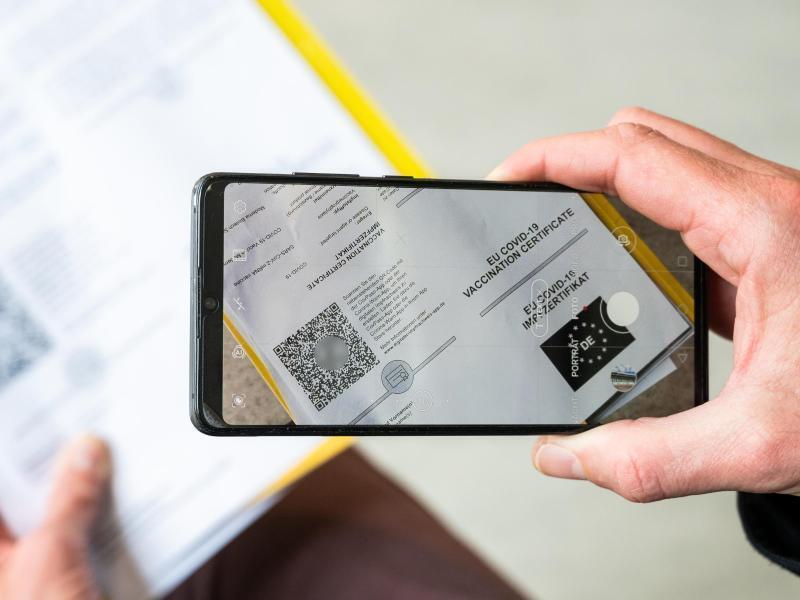 Ein Mann scannt mit einem Handy ein Dokument für den digitalen Impfnachweis. Foto: Christophe Gateau/dpa