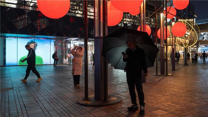 Bilder des Tages Ein Mann schaut auf sein Telefon in der Nähe von roten Zierkugeln am Taikoo Li Sanlitun Einkaufszentrum in Peking.