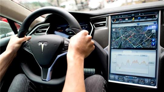 Ein Mann sitzt in einem Tesla Model S am Lenkrad: Elon Musk sagt, er sei mit seinen Versprechen zu selbstfahrenden Autos oft zu optimistisch gewesen.
