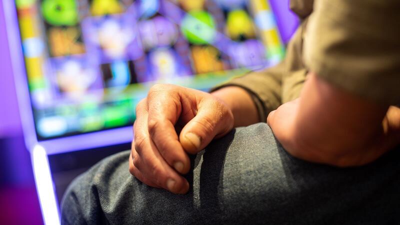 Ein Mann sitzt in einer Kneipe an einem Spielautomat.