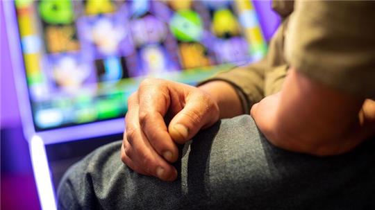 Ein Mann sitzt in einer Kneipe an einem Spielautomat.