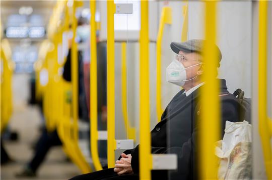 Ein Mann sitzt mit FFP2-Maske in der U-Bahn. Foto: Christoph Soeder/dpa