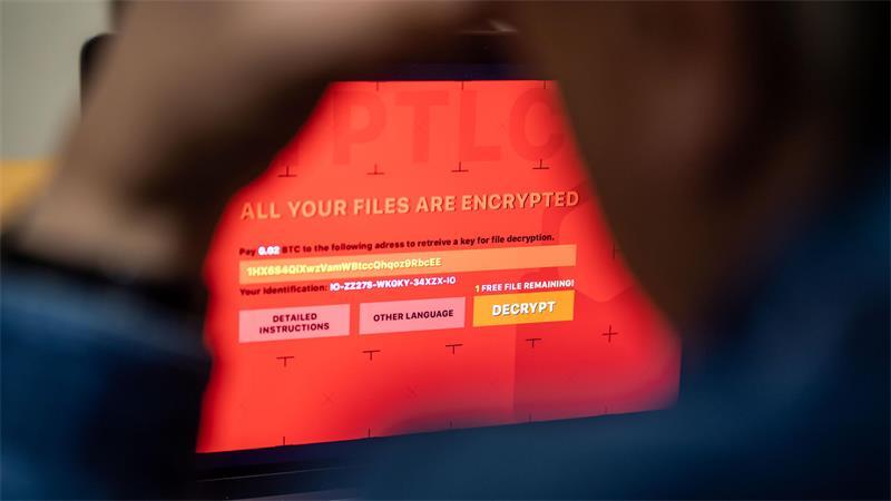 Ein Mann sitzt vor einem Laptop, der mit einem fiktiven Verschlüsselungstrojaner (Ransomware) befallen ist. Bei Angriffen mit Erpressungssoftware werden Daten auf Computern verschlüsselt, und die Hacker verlangen Geld für die Freigabe.