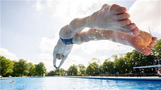 Ein Mann springt zur Eröffnung der Freibadsaison mit einem Kopfsprung ins Becken eines Freibades. (Symbolbild)