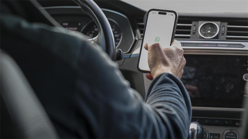 Hilfe! Das Handy klingelt andauernd, aber niemand ist dran Ein Mann sitzt mit einem Handy am Steuer eines Wagens.
