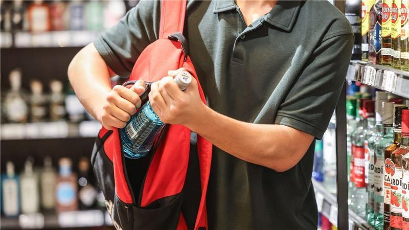 Ein Mann steckt eine Flasche in seinen Rucksack. Eine Person hat ihn im Auge: der Bremerhavener Supermarktdetektiv Andreas Hausner.