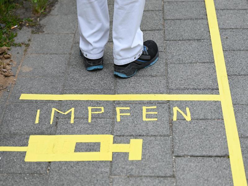 Ein Mann steht am Covid-19 Impfcenter hinter einer Bodenmarkierung mit der Aufschrift "Impfen" und einer Spritze. Foto: Arne Dedert/dpa/POOL/dpa/Symbolbild