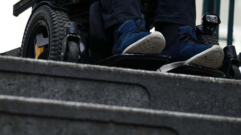 Abgeordnete mit Behinderungen vernetzen sich Ein Mann steht mit seinem Rollstuhl vor der Treppe eines Eingangs zur U-Bahn.