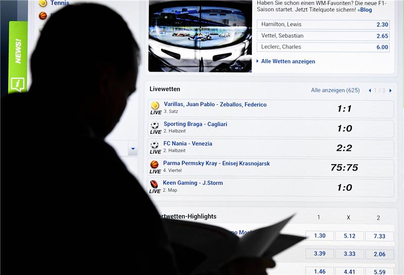 Ein Mann steht vor einem Bildschirm mit einer Seite eines Anbieters für Sport-Wetten (bet-at-home). Politiker fordern mit Blick auf die EM 2024, Werbung für Sportwetten zu verbieten. Foto: Carsten Rehder/dpa