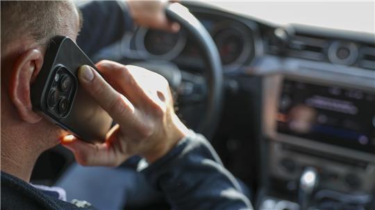 Ein Mann telefoniert in seinem Auto mit einem Smartphone. 
