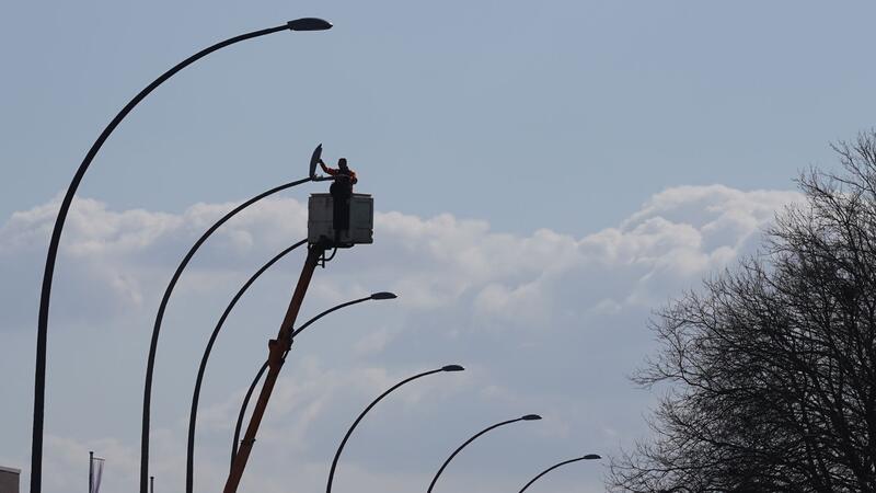 Ein Mann überprüft an der Schnackenburgallee in Hamburg eine Straßenlaterne.