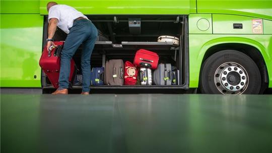 Ein Mann verstaut einen Koffer in einem Fernbus.