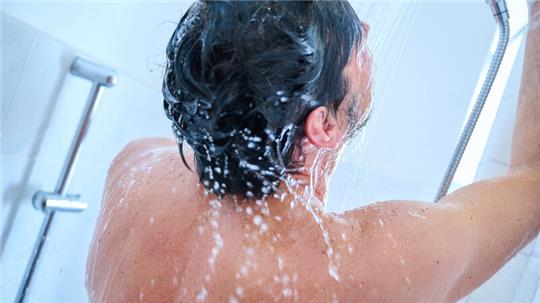Ein Mann wäscht sich unter der Dusche seine Haare