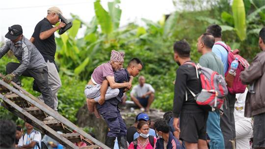 Ein Mann wird im Katastrophengebiet in Nepal von einem Polizisten auf dem Rücken getragen.